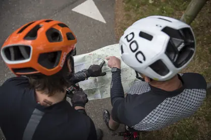 Twee fietsers met een helm kijken op een routekaart
